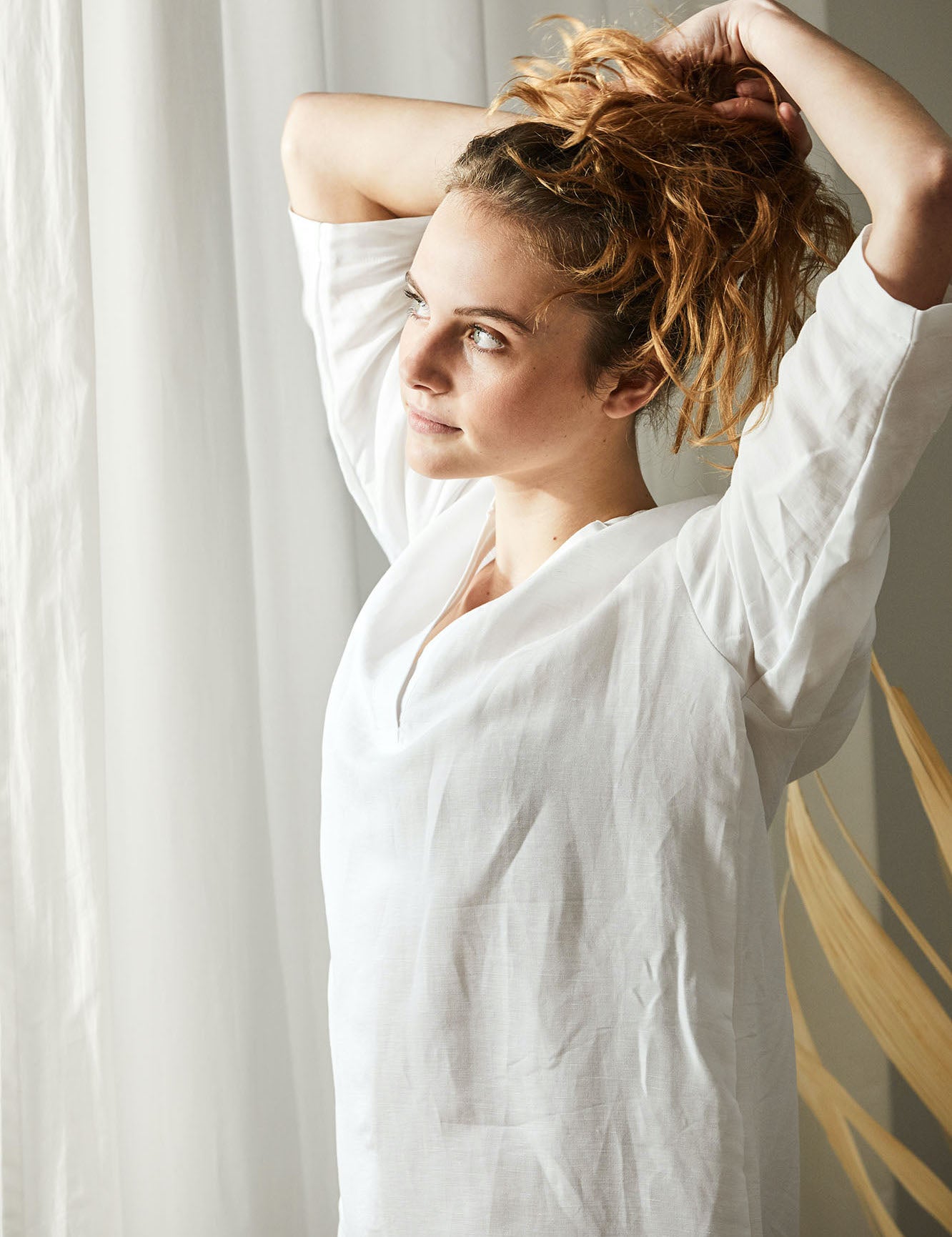 Frau mit Halbleinen Homewear blickt aus Fenster