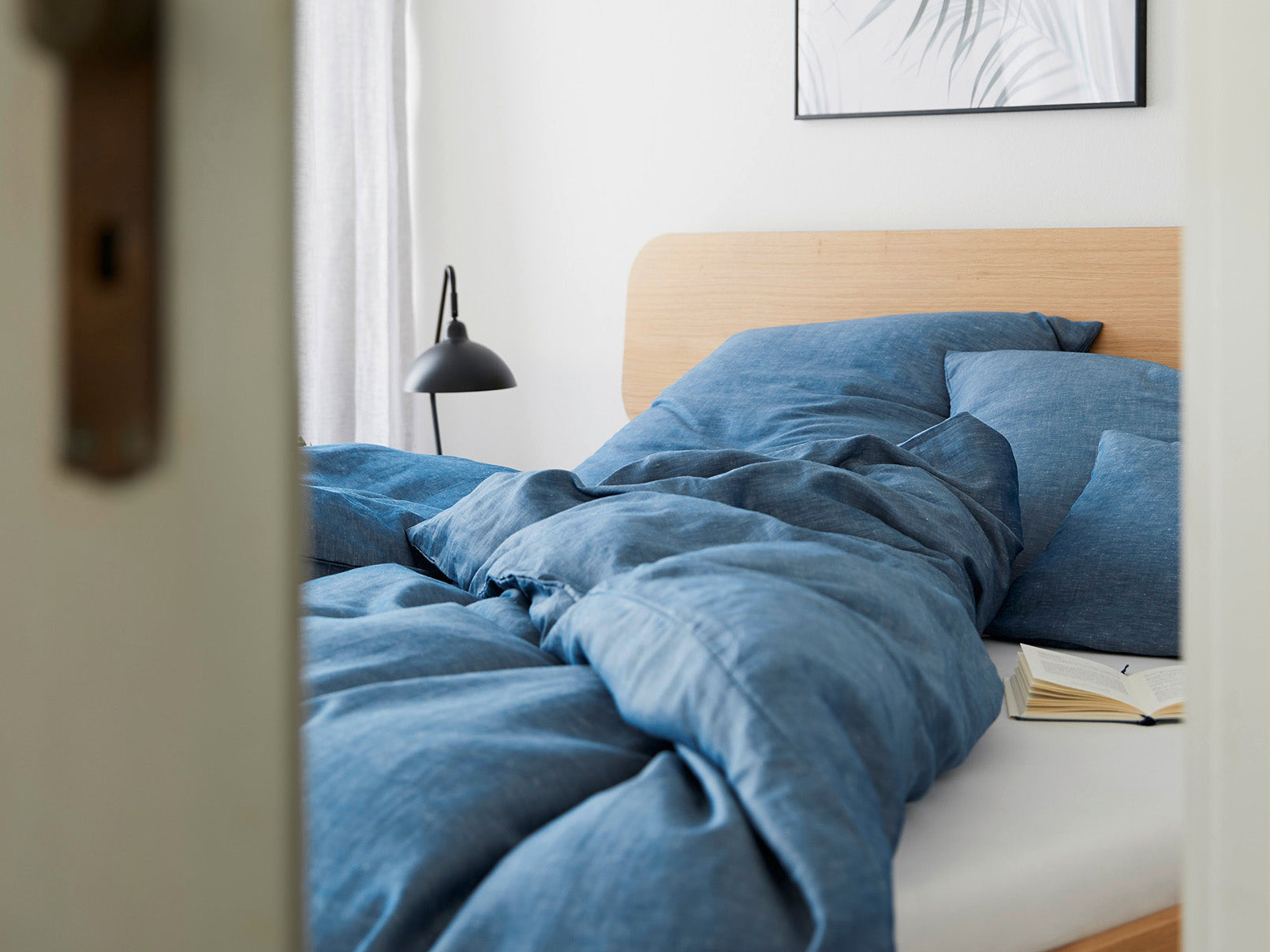 Gemütliches Bett mit blauer Halbleinen Bettwäsche
